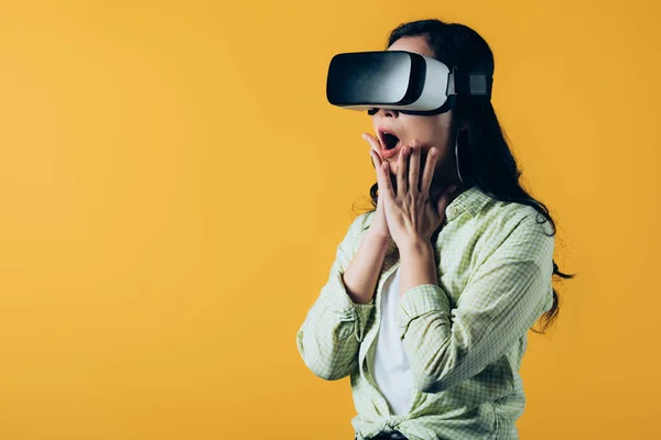 Chocado menina vestindo realidade virtual headset, isolado no amarelo — Fotografia de Stock