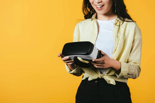 Изображение девушки, держащей гарнитуру виртуальной реальности, изолированной на желтом фоне — стоковое фото