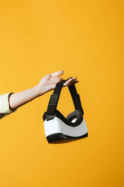 Partial view of girl holding Virtual reality headset, isolated on yellow — Stock Photo