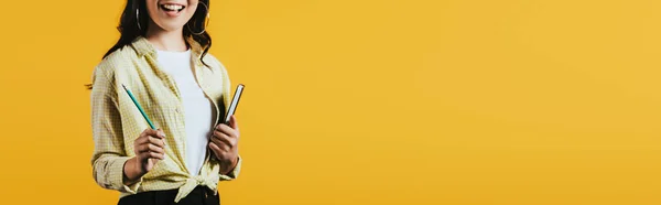 Cropped view of girl with notebook and pen, isolated on yellow — Stock Photo