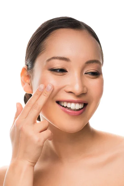 Приваблива усміхнена азіатська дівчина наносить крем, ізольована на білому — стокове фото