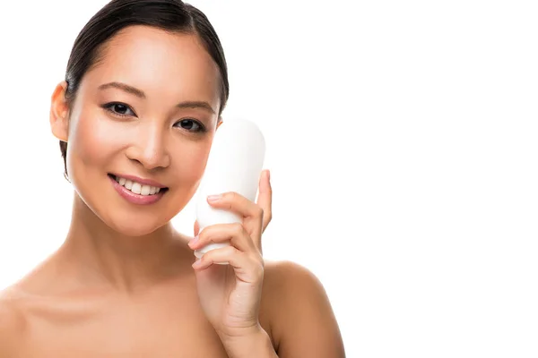 Atractiva mujer asiática sonriente con botella de loción, aislada en blanco - foto de stock