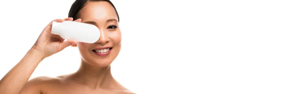 Усміхнена азіатська дівчина з пляшкою лосьйону, ізольована на білому — стокове фото