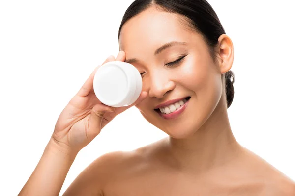 Attrayant asiatique fille avec les yeux fermés tenant crème cosmétique, isolé sur blanc — Photo de stock