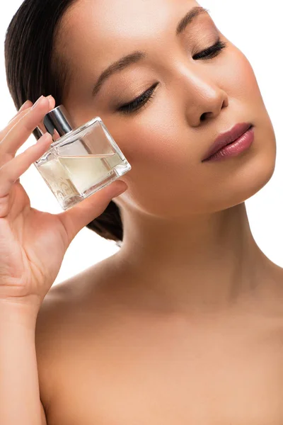 Tendre asiatique femme avec les yeux fermés tenant parfum, isolé sur blanc — Photo de stock