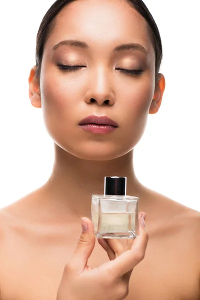 Tendre asiatique femme avec les yeux fermés tenant bouteille de parfum, isolé sur blanc — Photo de stock