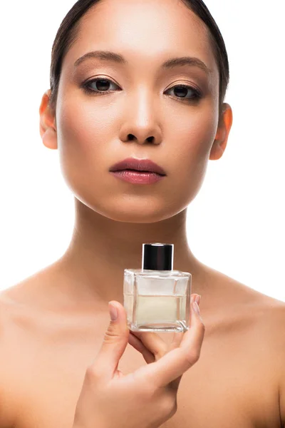 Attraente donna asiatica con la cura della pelle tenendo bottiglia di profumo, isolato su bianco — Foto stock