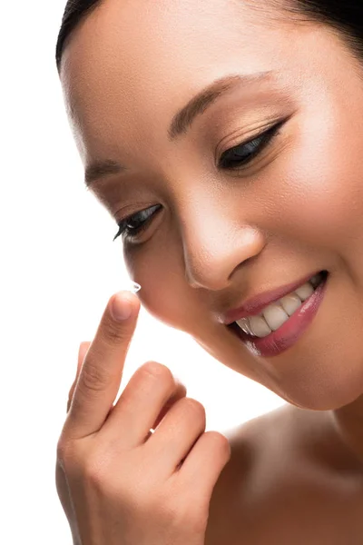 Усміхнена азіатська жінка тримає контактну лінзу, ізольована на білому — стокове фото