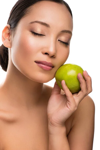 Tierna mujer asiática con los ojos cerrados sosteniendo manzana verde, aislado en blanco - foto de stock