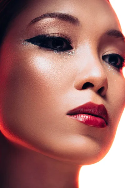 Schöne asiatische Frau mit Make-up in rotem Licht, isoliert auf weiß — Stockfoto