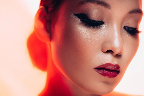 Attractive asian girl with makeup in red light — Stock Photo