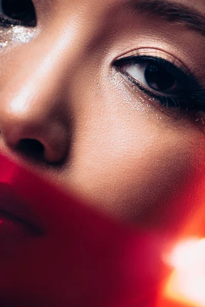Primer plano de chica asiática con maquillaje en luz roja, imagen tonificada - foto de stock