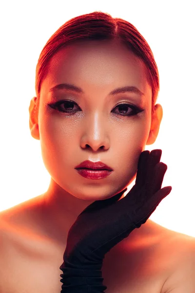 Красива азіатська дівчина в чорних рукавичках з макіяжем у червоному світлі, ізольована на білому — стокове фото