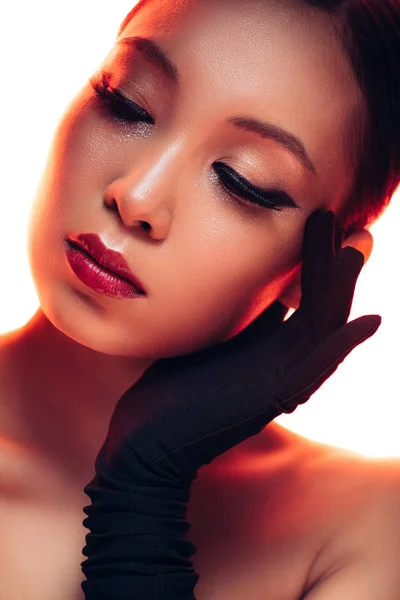 Tierna chica asiática en guantes negros con maquillaje en luz roja, aislado en blanco - foto de stock
