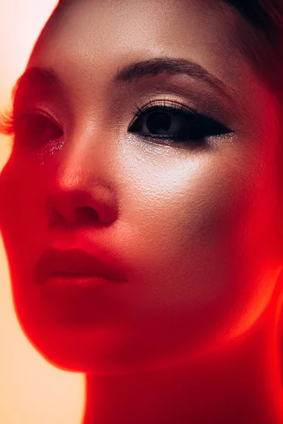 Gros plan de belle asiatique fille avec maquillage en rouge lumière — Photo de stock