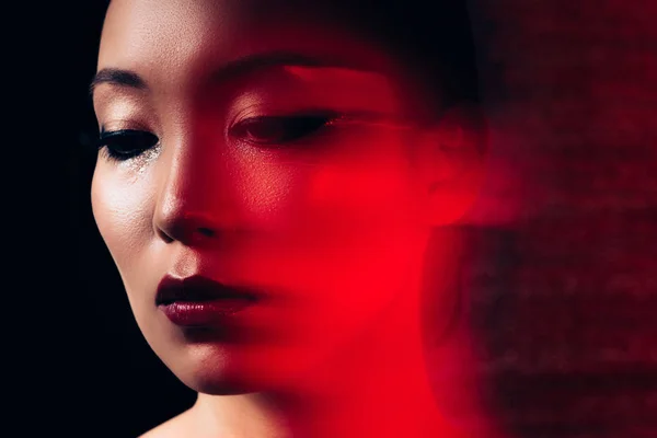 Atractivo asiático mujer con maquillaje en rojo luz - foto de stock