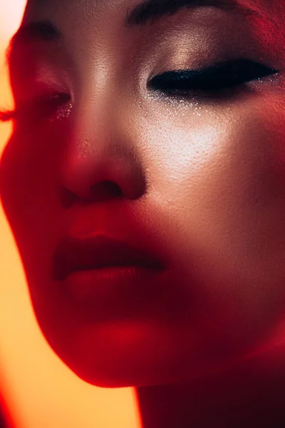 Close up of tender asian girl with makeup in red light — Stock Photo