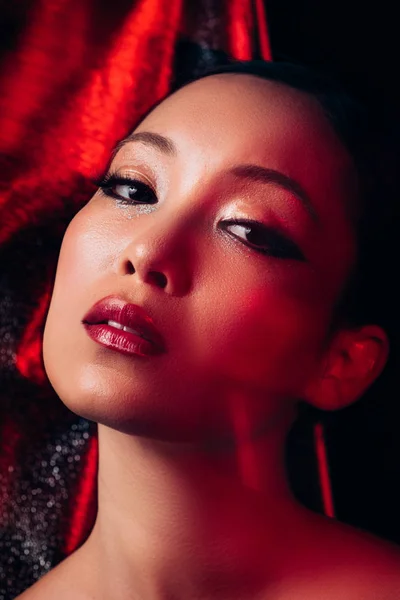 Seductive attractive asian girl with makeup in red light — Stock Photo
