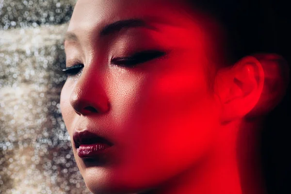 Primer plano de sexy chica asiática con los ojos cerrados en luz roja - foto de stock