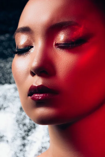 Close up of seductive asian girl with closed eyes in red light — Stock Photo