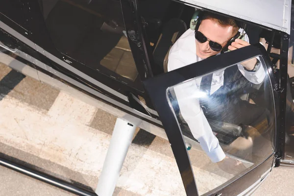 Top view of Pilot in sunglasses and headset sitting in helicopter cabin with copy space — Stock Photo