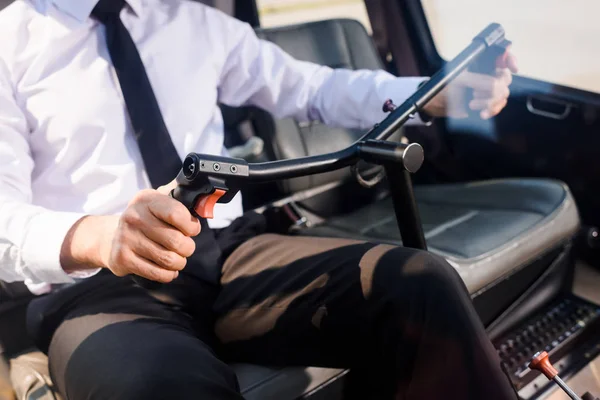 Teilansicht des Piloten in offizieller Kleidung, der in der Helikopterkabine sitzt und das Lenkrad hält — Stockfoto