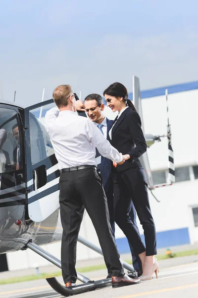 Uomini d'affari in abbigliamento formale vicino elicottero e pilota — Foto stock