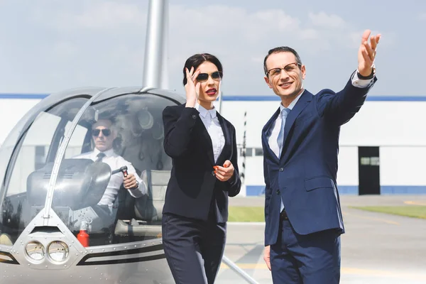 Бізнесмени в костюмах жестикулюють біля вертольота з пілотом — стокове фото
