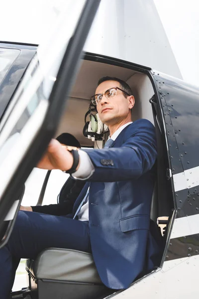 Vue à faible angle de l'homme d'affaires en tenue de cérémonie assis dans la cabine de l'hélicoptère — Photo de stock