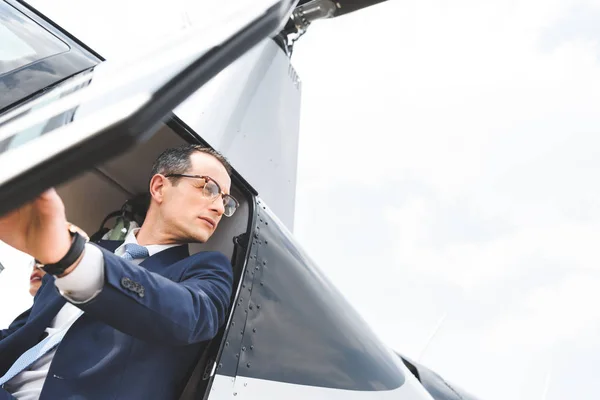 Low angle view of businessman in formal wear sitting in helicopter cabin with copy space — Stock Photo