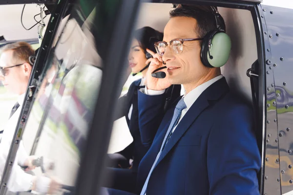 Enfoque selectivo de hombre de negocios en auriculares sentado en cabina de helicóptero - foto de stock