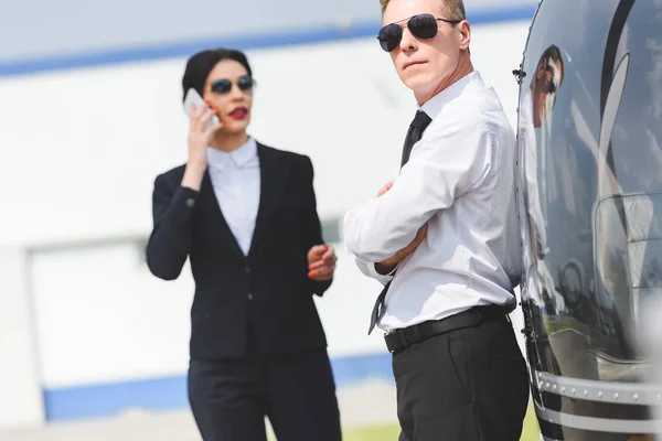 Geschäftsfrau telefoniert mit Smartphone in der Nähe von Pilot und Hubschrauber — Stockfoto