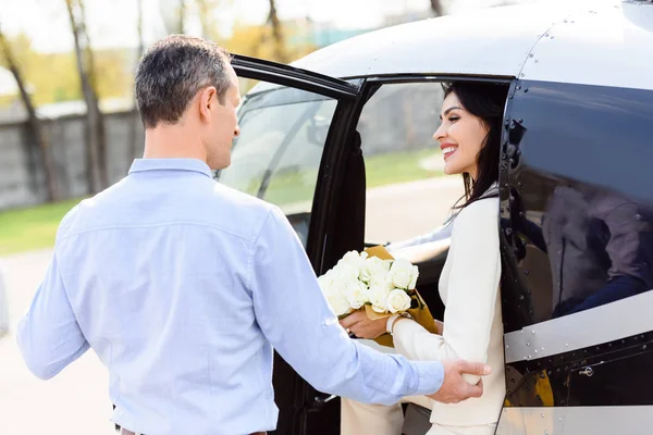 Schöne Frau mit Blumen sitzt bei romantischem Date im Hubschrauber und schaut Ehemann an — Stockfoto