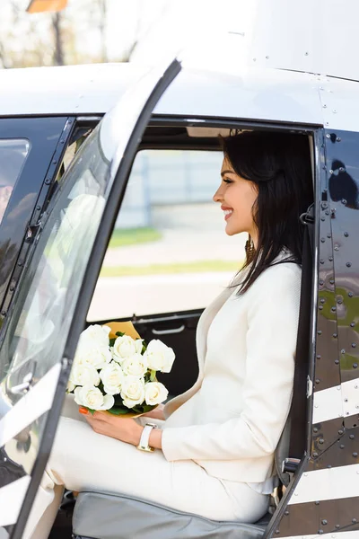 Schöne lächelnde Frau mit Blumen im Hubschrauber sitzend — Stockfoto