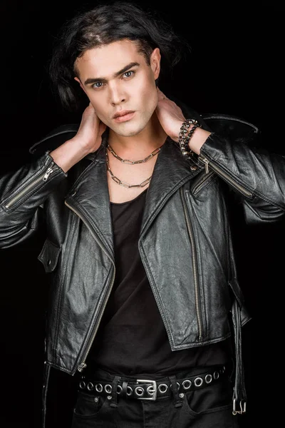 Handsome man in leather jacket touching neck and looking at camera isolated on black — Stock Photo