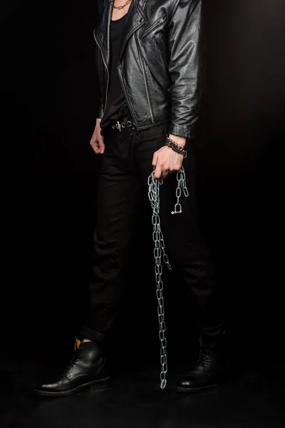 Cropped view of man standing and holding metallic chains on black — Stock Photo