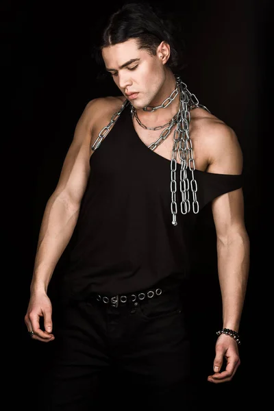 Displeased man in tank top standing with chains on shoulders isolated on black — Stock Photo