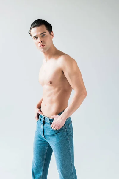 Handsome man touching blue jeans while standing on white — Stock Photo