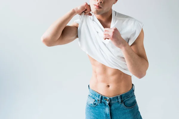 Vue recadrée de l'homme décollant t-shirt blanc et debout sur blanc — Photo de stock