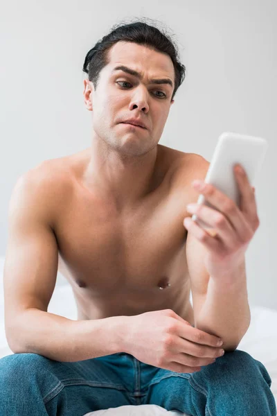Selektiver Fokus des hemdslosen Mannes, der zu Hause auf das Smartphone schaut — Stockfoto