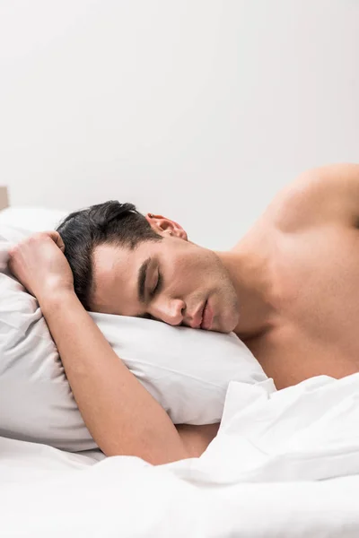 Красивый и без рубашки мужчина лежит на кровати с закрытыми глазами — стоковое фото