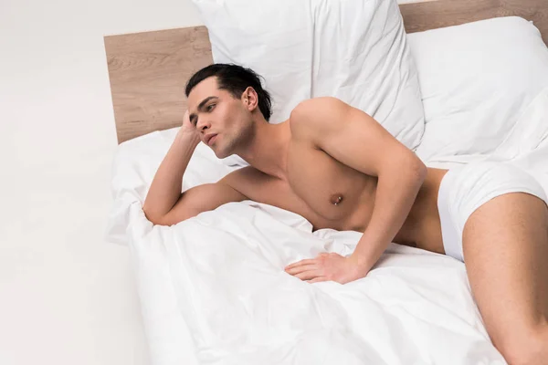 Bonito muscular e sem camisa homem em roupa interior deitado na cama — Fotografia de Stock