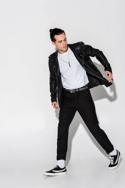 Handsome and stylish man in leather jacket walking on white — Stock Photo