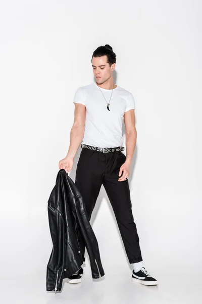 Man in white t-shirt looking at black leather jacket on white — Stock Photo