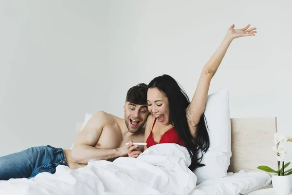 Feliz asiático mujer gesto mientras celebración embarazo prueba cerca sonriendo novio - foto de stock