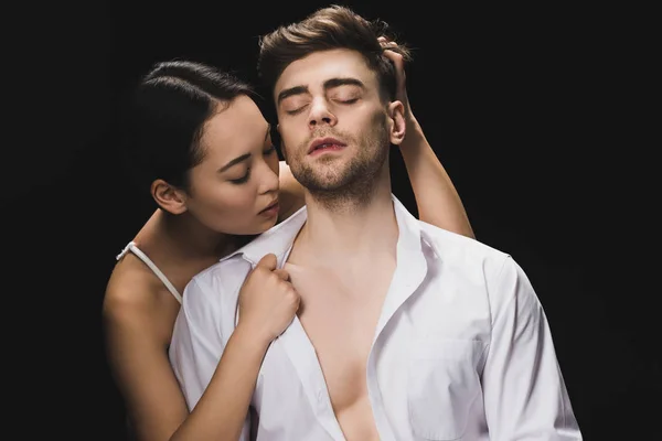 Beautiful asian woman embracing handsome boyfriend in white shirt isolated on black — Stock Photo