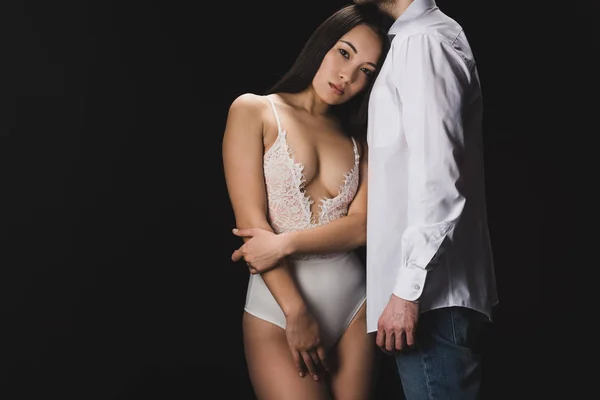Attractive asian woman in white lingerie standing near boyfriend in white shirt isolated on black — Stock Photo