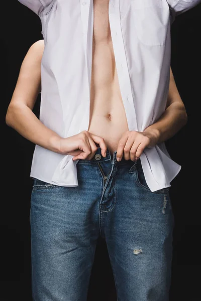 Vue partielle de la femme déshabiller petit ami en jeans bleu isolé sur noir — Photo de stock