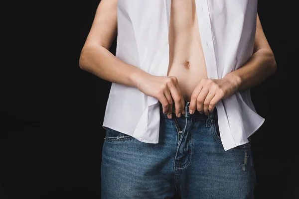 Corte vista de mulher despir namorado em jeans azul isolado no preto — Fotografia de Stock