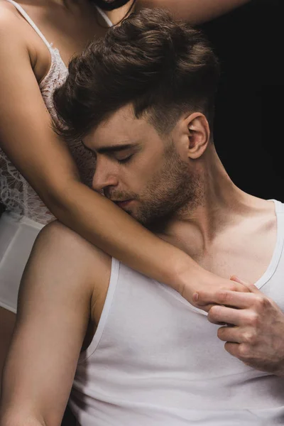Recortado vista de mujer en blanco lencería cerca guapo hombre besos su mano aislado en negro - foto de stock